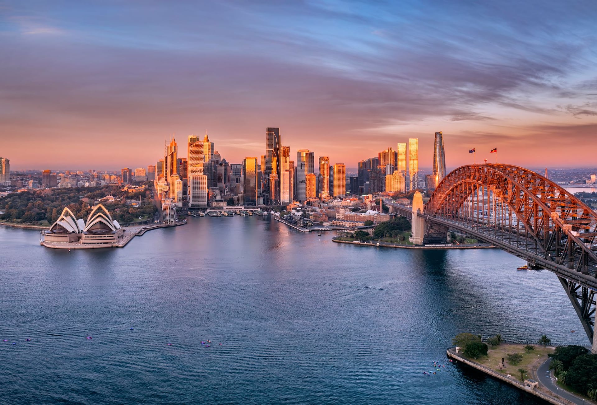 Aerial view of Sydney Harbour at sunset with the Opera House and Harbour Bridge