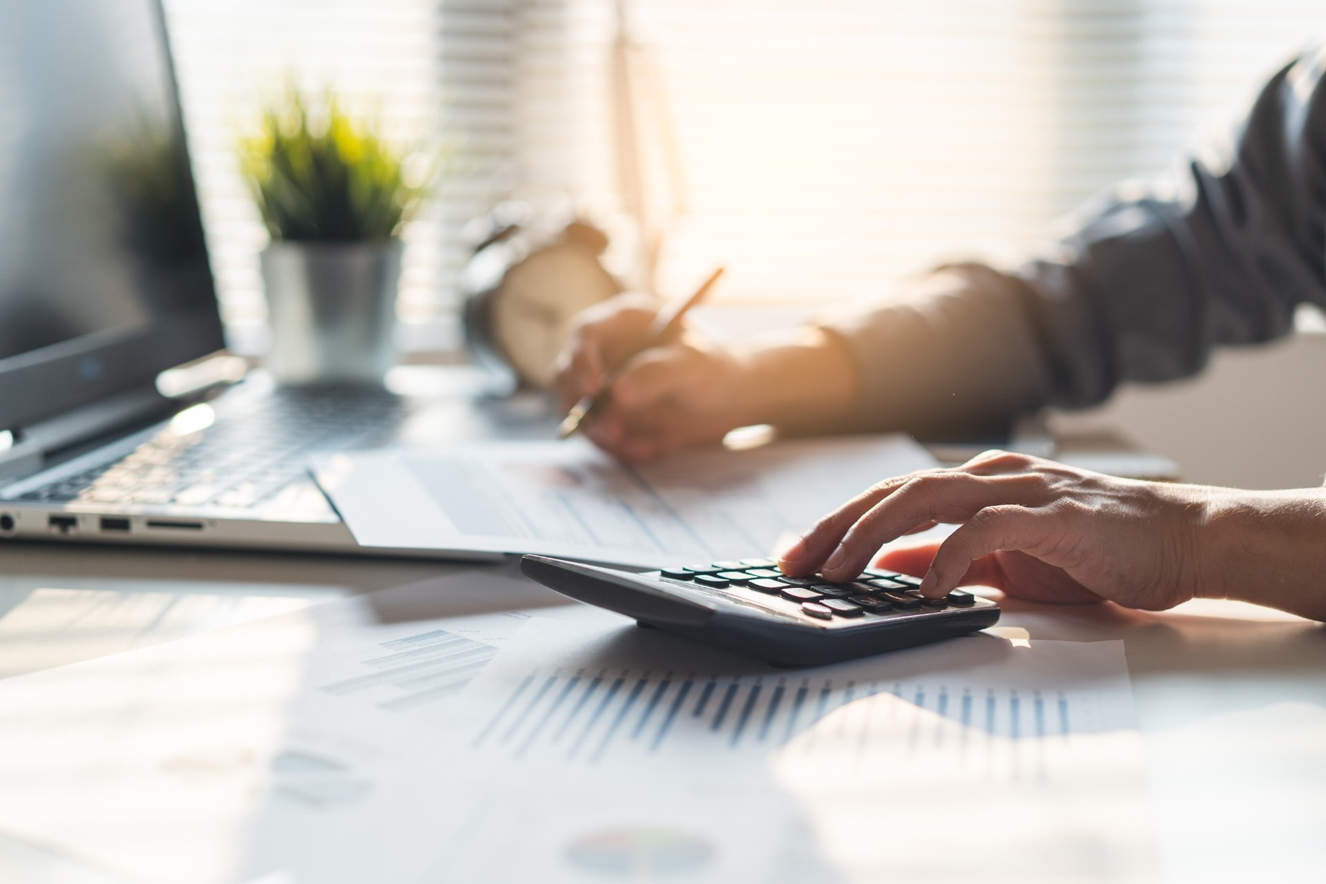 Accountant working through figures with a calculator and reports