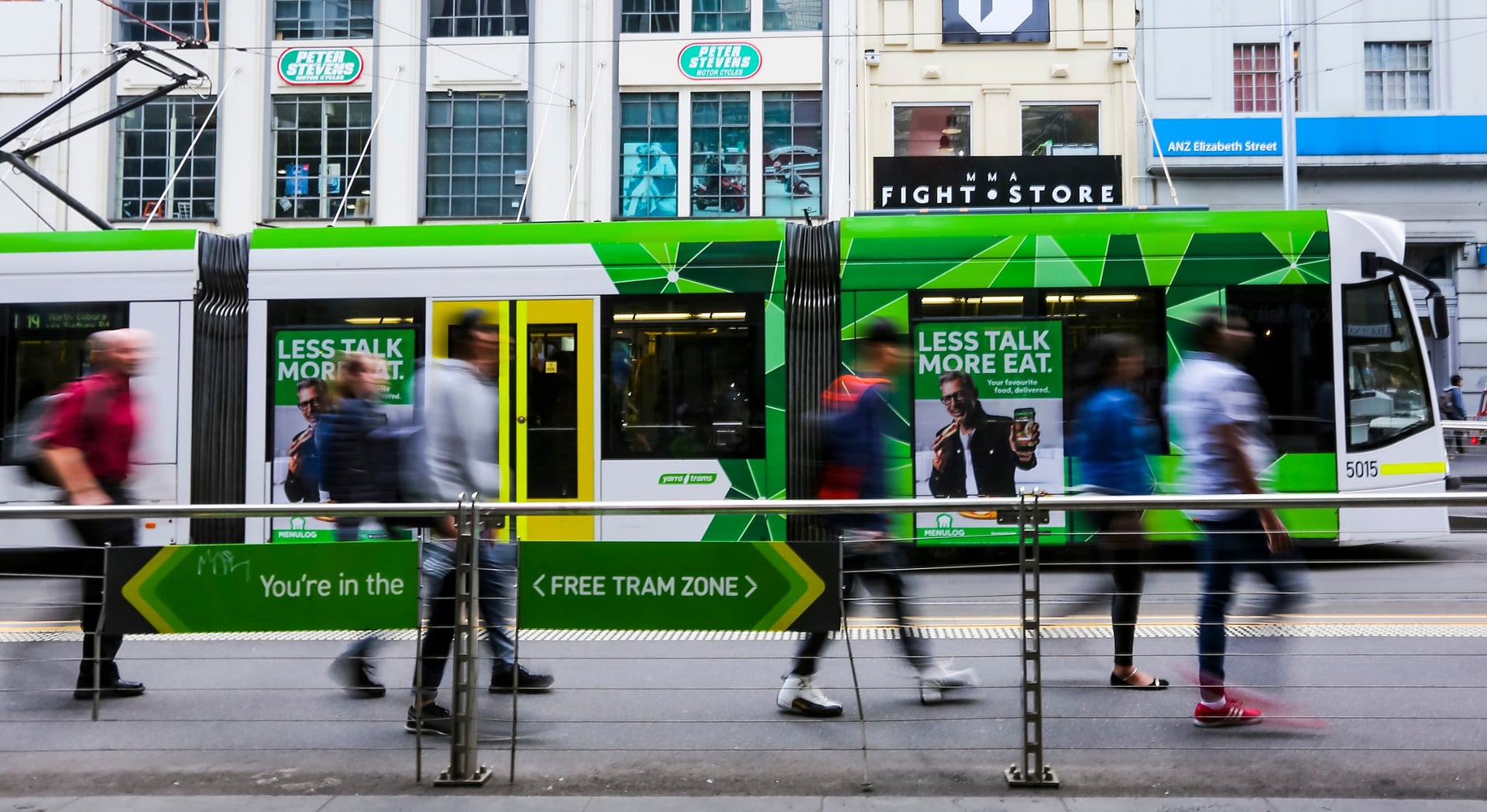 A tram passing pedestrians on a Melbourne city street