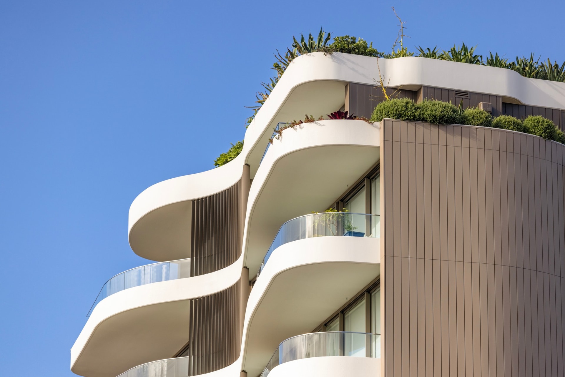 Curved balconies of a modern apartment building against a blue sky