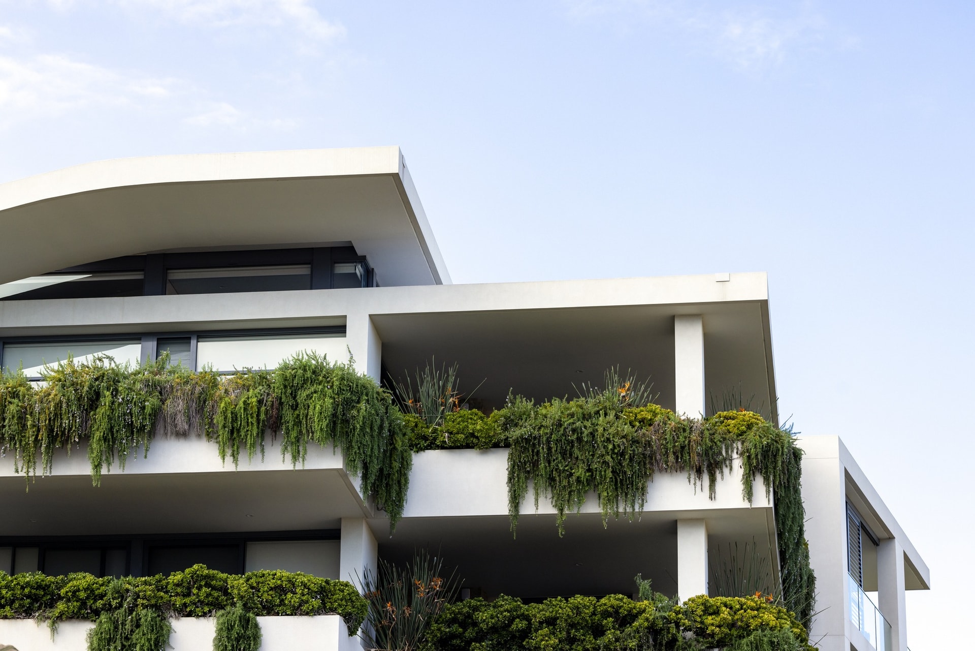 Modern apartment building with planted balconies against a clear sky